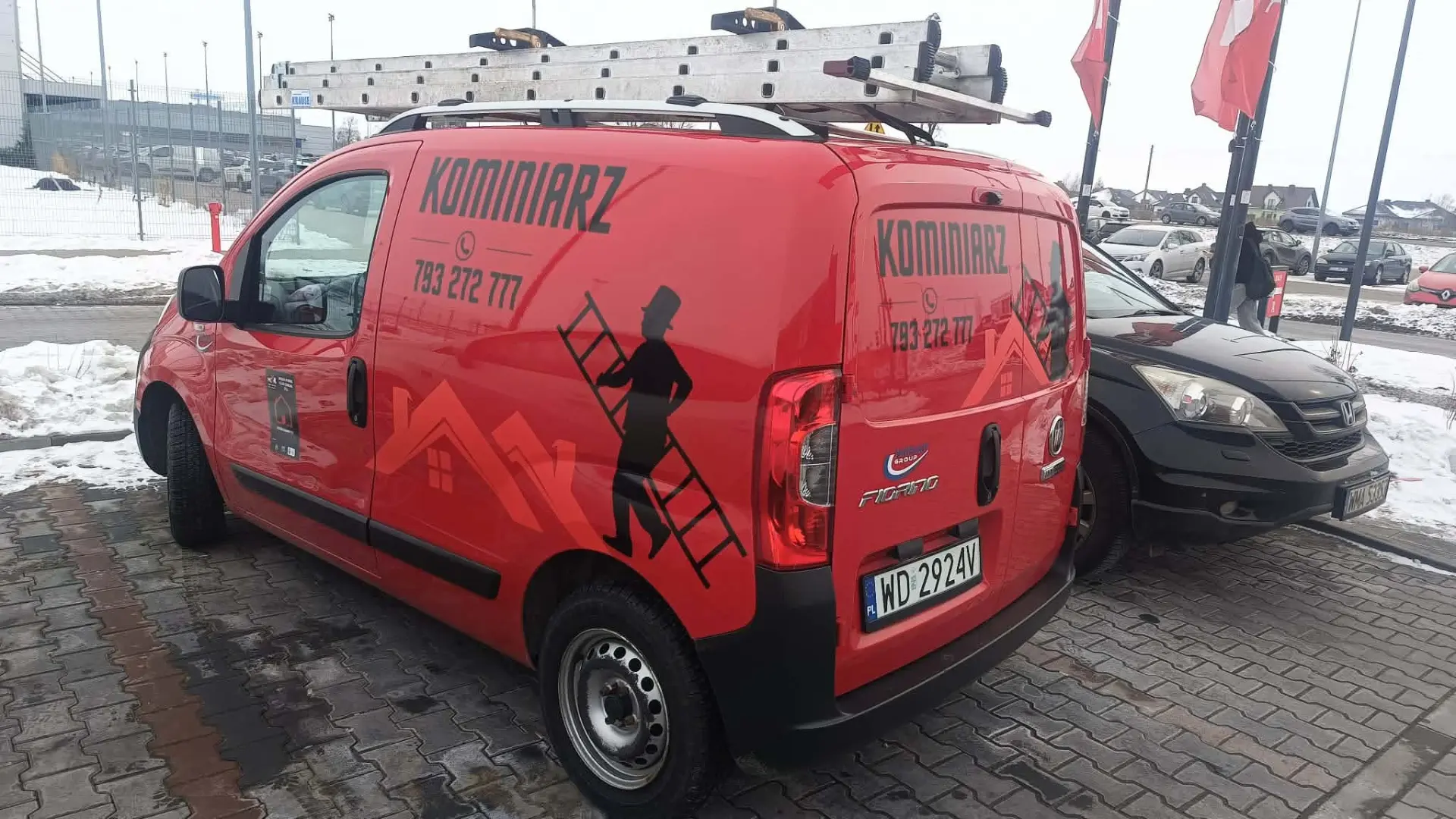 Czerwony samochód firmowy z napisem KOMINIARZ i numerem 793 272 777